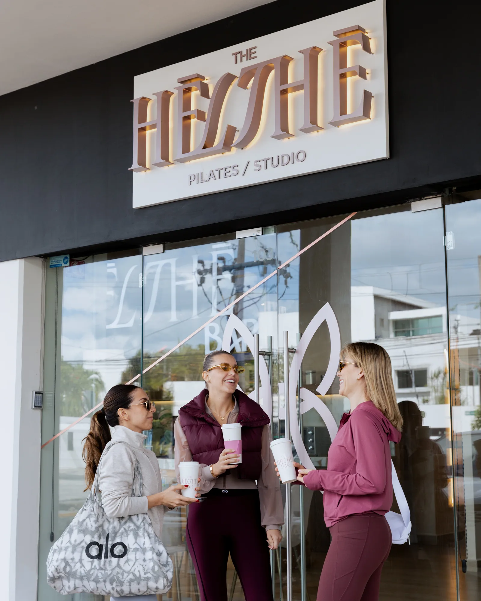 Fachada de The Hēlthē Pilates Studio con alumnas saliendo de clase