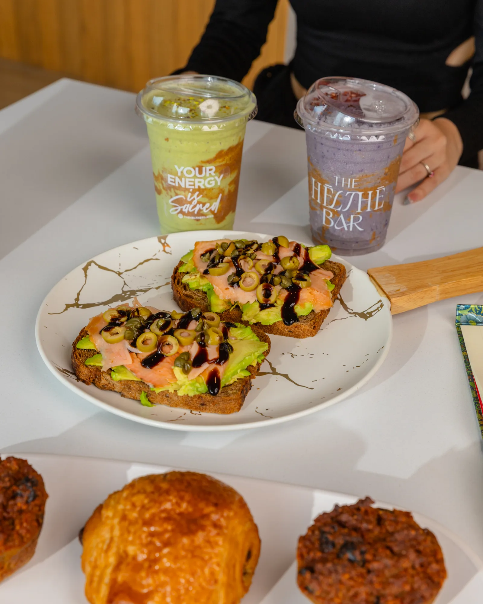 Toasts, smoothies y panes en una mesa de The Hēlthē Bar