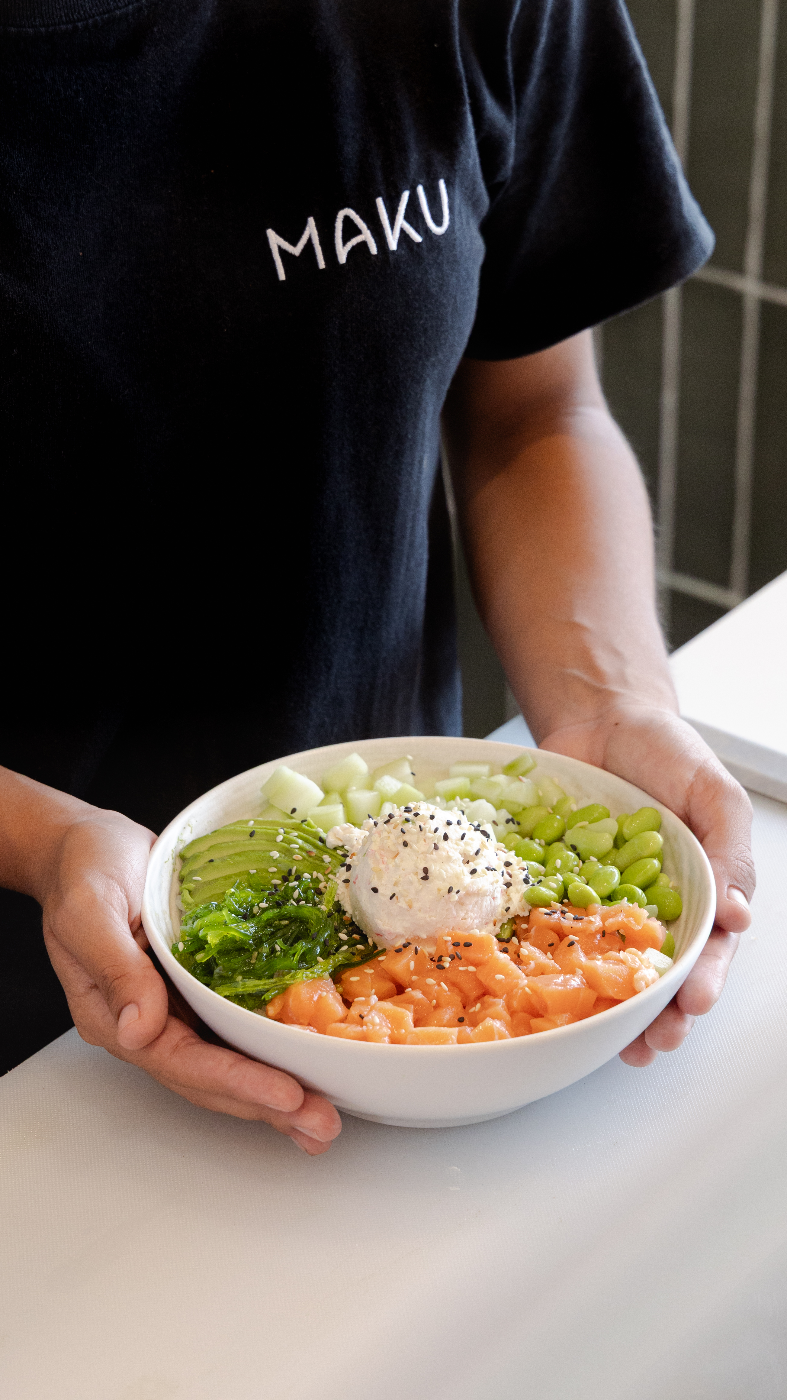 Staff sosteniendo bowl de salmón con branding Maku