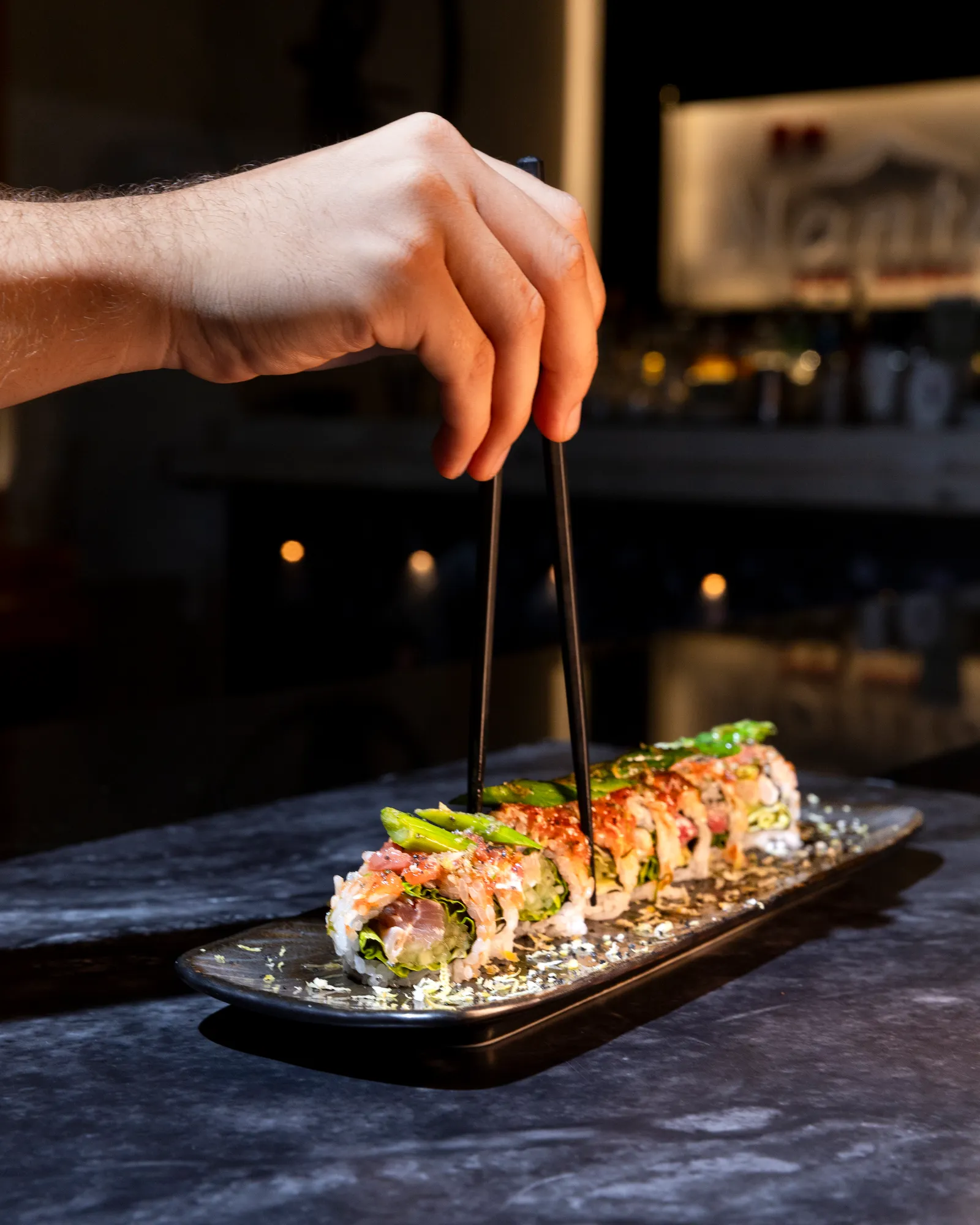 Nantai chef serving a sushi roll at the bar