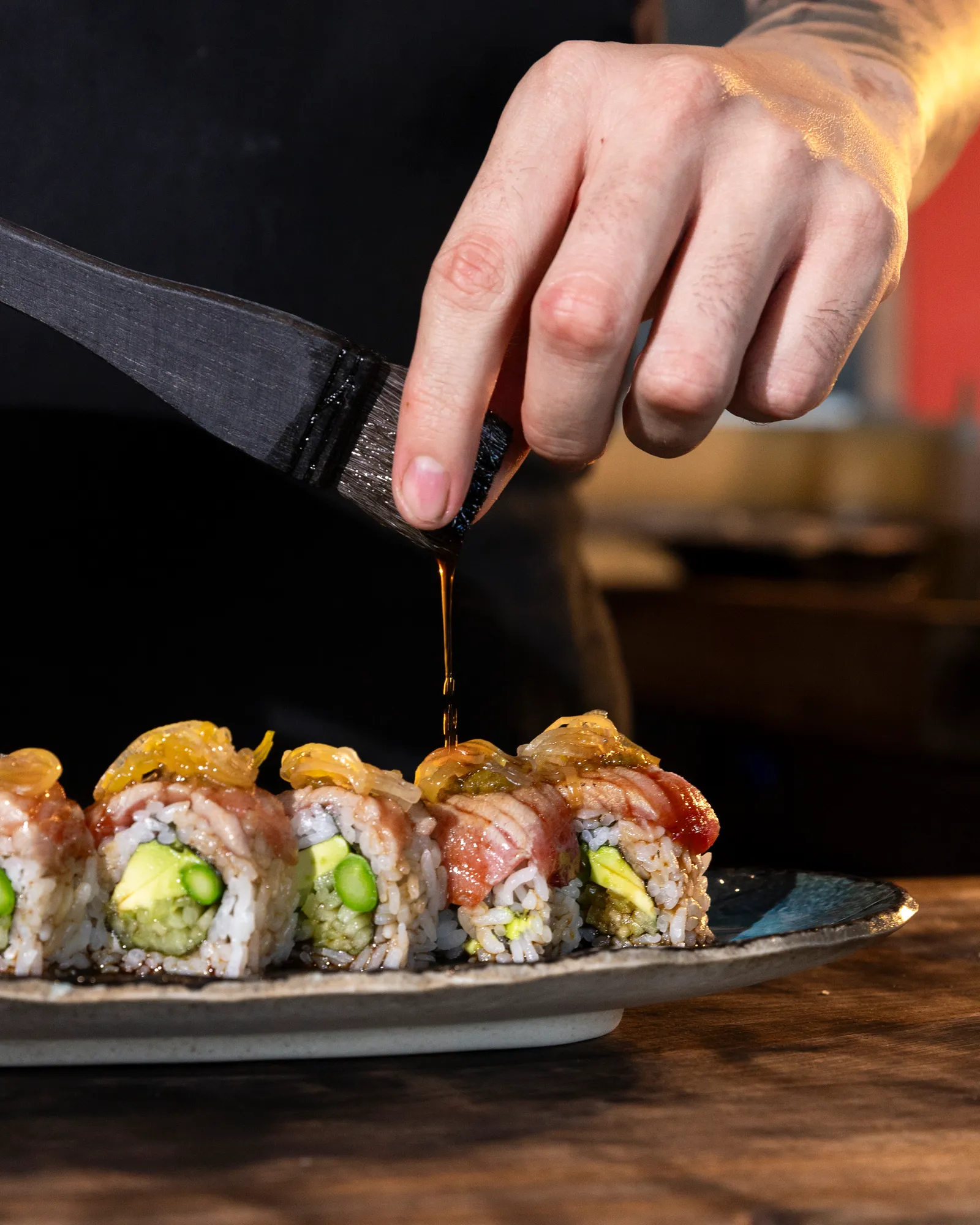 Sushi roll brushed with glaze as it's served