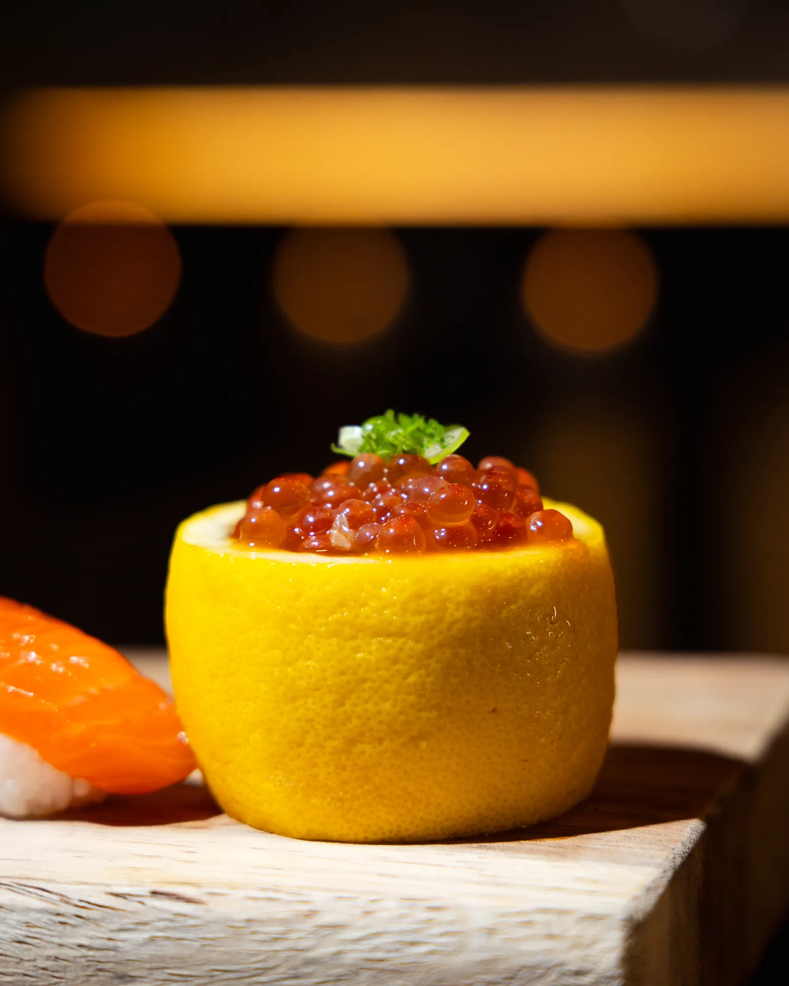 Ikura served in a lime next to a salmon nigiri